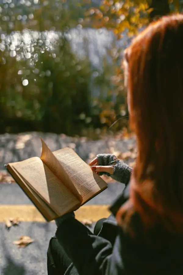 Женщина читает книгу в парке на скамейке